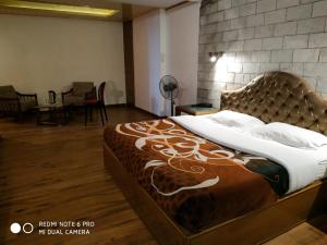 西姆拉Hotel Lords Regency的一间卧室配有一张大床,配有棕色和白色的毯子
