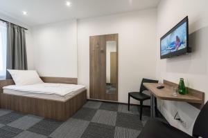 um quarto com uma cama, uma secretária e uma televisão em Hostel SMS em Bydgoszcz