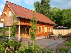 een houten huis met een patio en een tafel bij B&B De Lakenvelder in Venhorst