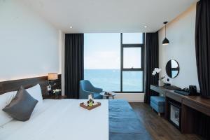 Schlafzimmer mit einem Bett, einem Schreibtisch und einem großen Fenster in der Unterkunft Phương Bắc Luxury Hotel in Dong Hoi