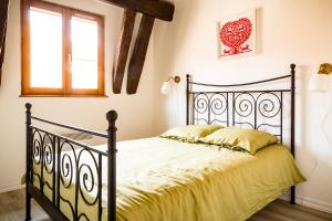 a bedroom with a black bed with yellow sheets and a window at Résidence des Tanneurs - Sylvaner in Obernai