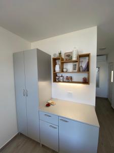 uma cozinha com armários brancos e um frigorífico branco em A lovely and cozy room with a breathtaking view 2 em Vis