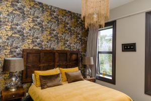 a bedroom with a bed with yellow sheets and a floral wallpaper at The Old Confectionery in Oamaru