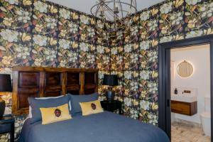 a bedroom with a blue bed with a floral wallpaper at The Old Confectionery in Oamaru