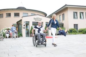 a woman pushing a man in a wheel chair at Seehotel Rheinsberg in Rheinsberg