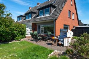 a house with a patio with a table and chairs at Haus 32 in Wenningstedt