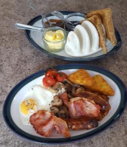 two plates of breakfast food with eggs bacon and toast at Mango Lodge in Kent