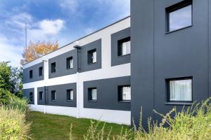 a black and white building with grass in front of it at B&B HOTEL Angers Parc Expos in Saint-Sylvain-dʼAnjou