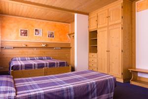 two beds in a room with wooden walls at Hotel Centrale in Alleghe