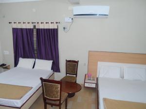 a bedroom with two beds and a table and chairs at Hotel Pasuparthy Residency in Tirupati