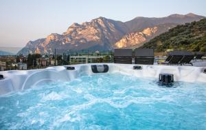 a hot tub with chairs and mountains in the background at HOODY ACTIVE & HAPPINESS HOTEL in Arco