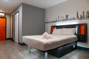 a bedroom with a large bed with white sheets at easyHotel London City Shoreditch in London