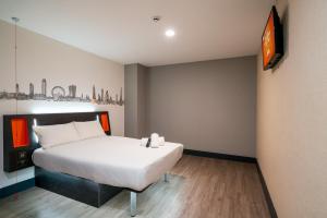 um quarto com uma cama e uma televisão na parede em easyHotel London City Shoreditch em Londres