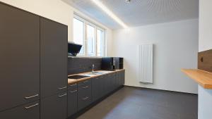 a kitchen with black cabinets and a sink at The Bunk Hostel in Essen