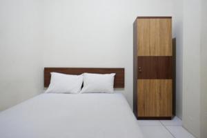 a bedroom with a white bed and a wooden cabinet at KoolKost at Jl Unta Pandeyan Lamper Semarang - Minimum Stay 30 night in Semarang
