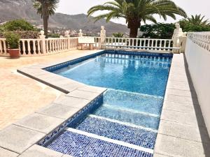 a swimming pool with blue water and palm trees at Detached villa, private pool only 10 minutes to beaches in Valle de San Lorenzo