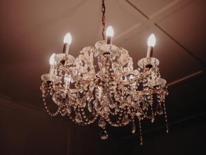 a chandelier hanging from a ceiling with three candles at Genesta House in Cowes