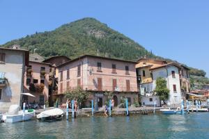 a group of buildings on the water with a mountain at La dimora dei pescatori in Monte Isola
