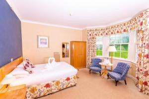 a bedroom with a bed and two chairs and a window at Green Hotel in Kinross