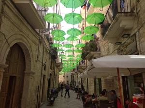 un groupe de parapluies verts suspendus au-dessus d'une rue dans l'établissement House Mattia, à Bari