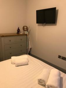 a bedroom with a bed with two towels and a tv at Belmont - Y Prom in Aberystwyth