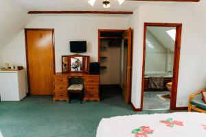 a bedroom with a bed and a dresser and a mirror at The Farmhouse Lochmeyler in Llandeloy