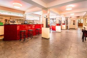 une cuisine avec des placards rouges et des tabourets de bar dans l'établissement Hôtel Estival Arriel, à Lourdes