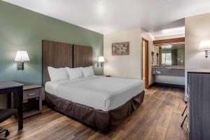 Cama grande en habitación de hotel con escritorio y cama en Econo Lodge Portland Airport en Portland