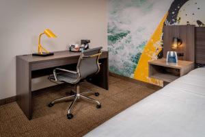 a room with a bed, desk, chair and lamp at Clarion Pointe Beckley in Beckley