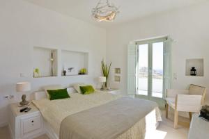 a white bedroom with a large bed with green pillows at w Villa Black Rock Santorini in Akrotiri