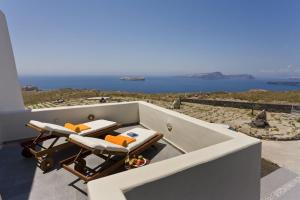 a couple of lounge chairs sitting on top of a balcony at w Villa Black Rock Santorini in Akrotiri