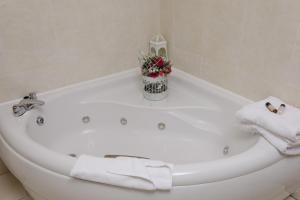 una vasca da bagno bianca con asciugamani e un vaso di fiori di Hamlet Court Hotel a Enfield