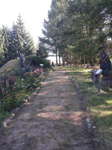 a dirt path with statues and flowers in a park at Uroczysko Ruczaj in Czarna Białostocka