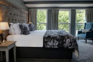a bedroom with a bed and a chair and windows at The Lord Street Hotel; BW Signature Collection in Southport