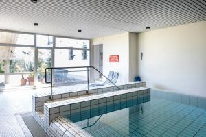 una piscina con 2 sillas en una habitación en Black Forest Schwarzwaldblick Indoorpool Natur Ruhe Komfort, en Höchenschwand