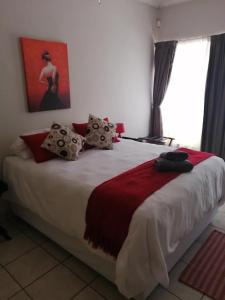 a bedroom with a large bed with a red and white blanket at Guesthaven B&B in Middelburg