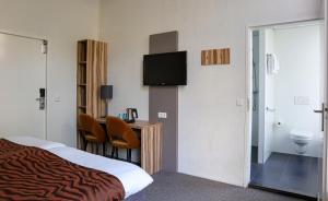 a hotel room with a bed and a television at Hotel Asterisk, a family run hotel in Amsterdam