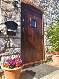 a wooden door with flowers in front of a stone building at The Coach House in Ruthin
