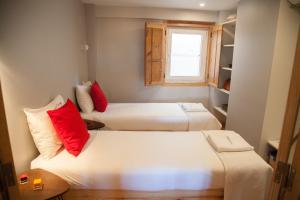 2 łóżka w małym pokoju z czerwonymi poduszkami w obiekcie FLH Duque Mezzanine with View w Lizbonie