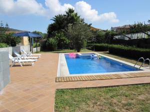 a swimming pool with two chairs and an umbrella at Casa Concha in Porto do Son