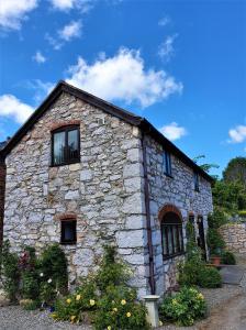 a stone building with windows and flowers in front of it at The Coach House in Ruthin