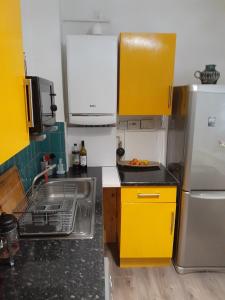 cocina con armarios amarillos, fregadero y nevera en BIG BEN'S SHADE, en Londres
