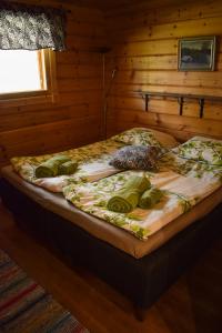 a bed in a room with a wooden wall at Puruvesi Holiday Villas, Kalliohovi in Hiukkajoki