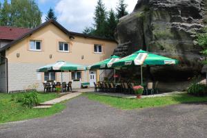 a building with tables and umbrellas in front of it at Penzion Pohoda in Jetřichovice