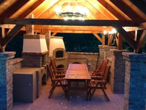 a wooden table and chairs on a patio with a fireplace at Vadszőlős Porta in Ispánk