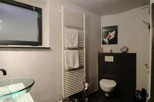ein Bad mit WC und ein TV an der Wand in der Unterkunft Art of Living in Plön