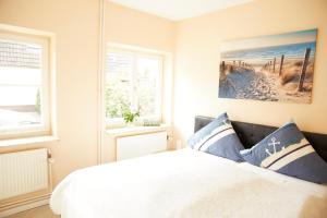 ein Schlafzimmer mit einem Bett und zwei Fenstern in der Unterkunft Ferienwohnungen Zum Goldenen Anker in Tönning