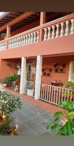 Casa de color rosa con porche y balcón en Piccola Pousada en Águas de São Pedro