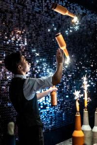 a man is holding up a bottle and torches at Arthur Hotel Zhujiang New Town Guangzhou in Guangzhou