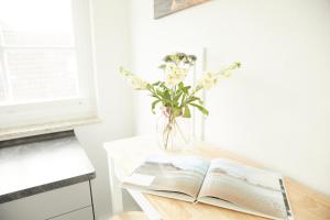 un libro abierto sobre una mesa con un jarrón de flores en Ferienwohnungen Zum Goldenen Anker, en Tönning